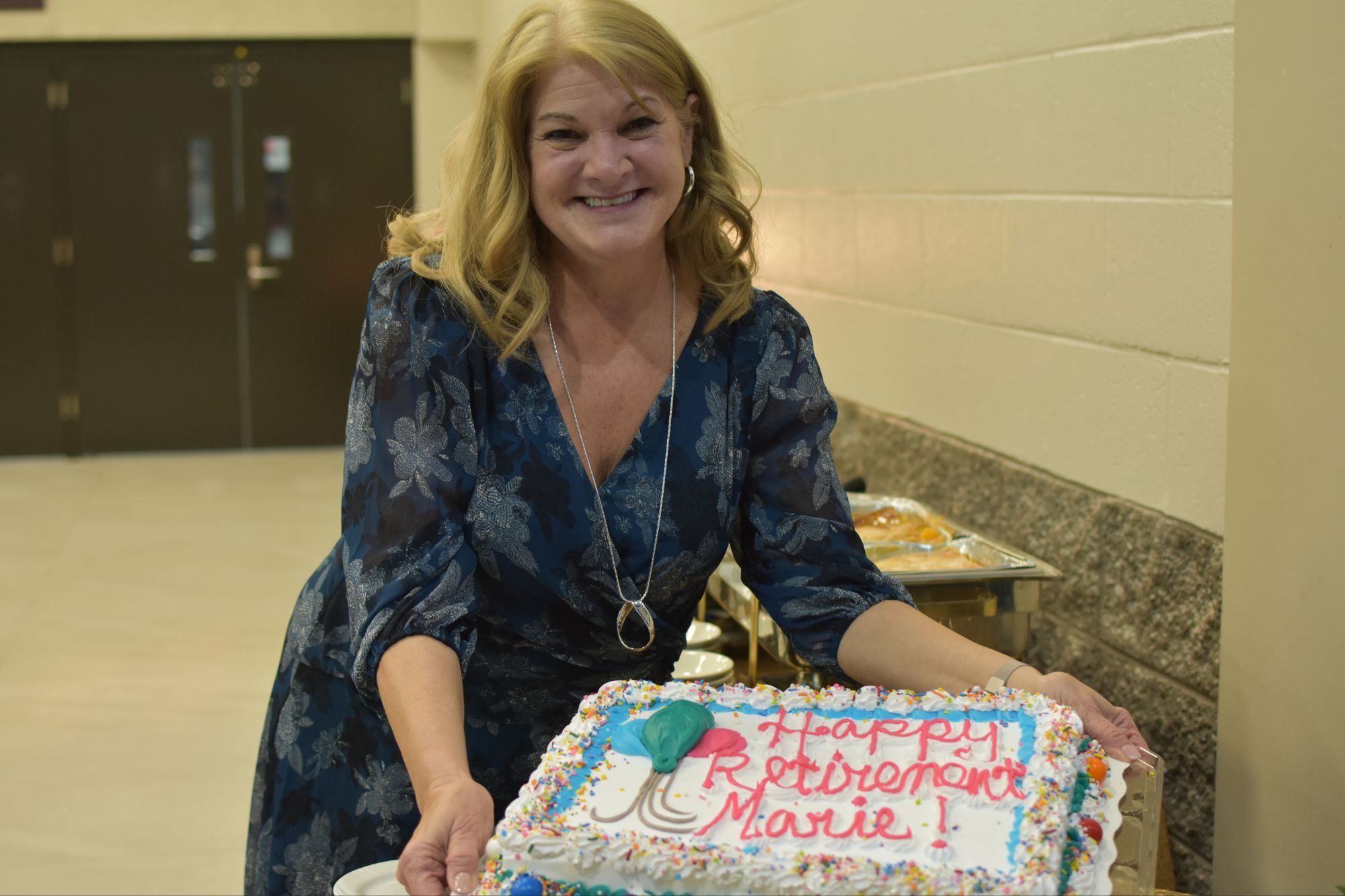 Photo of Marie Arighi at her retirement party holding her cake
