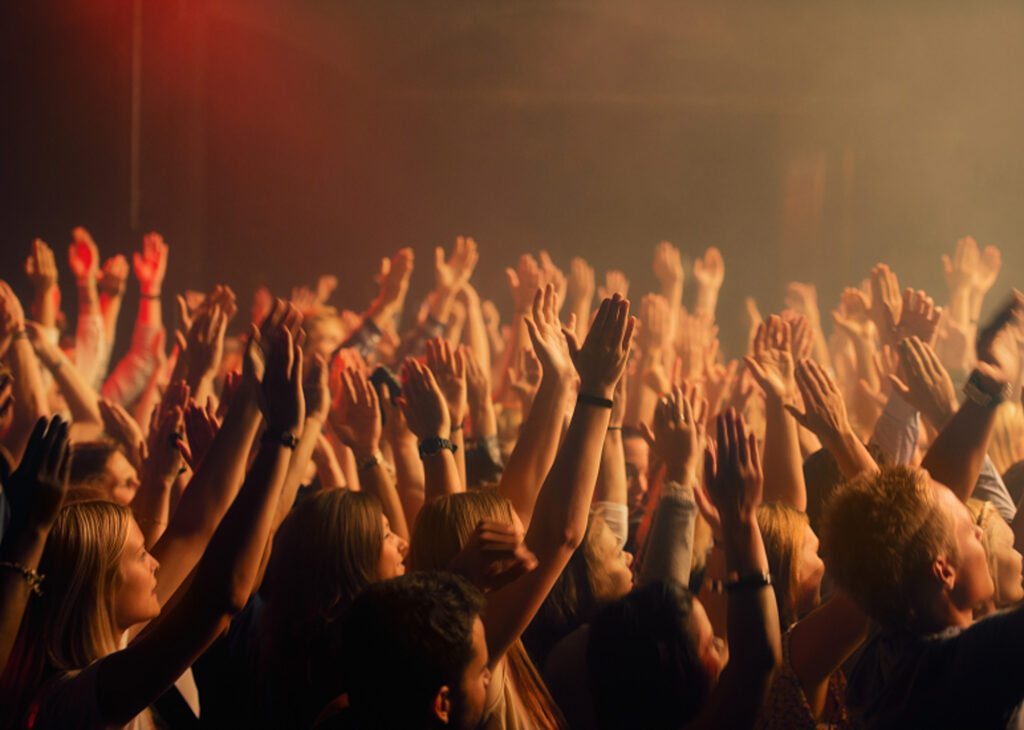 Image of a crowd with raised hands at a concert