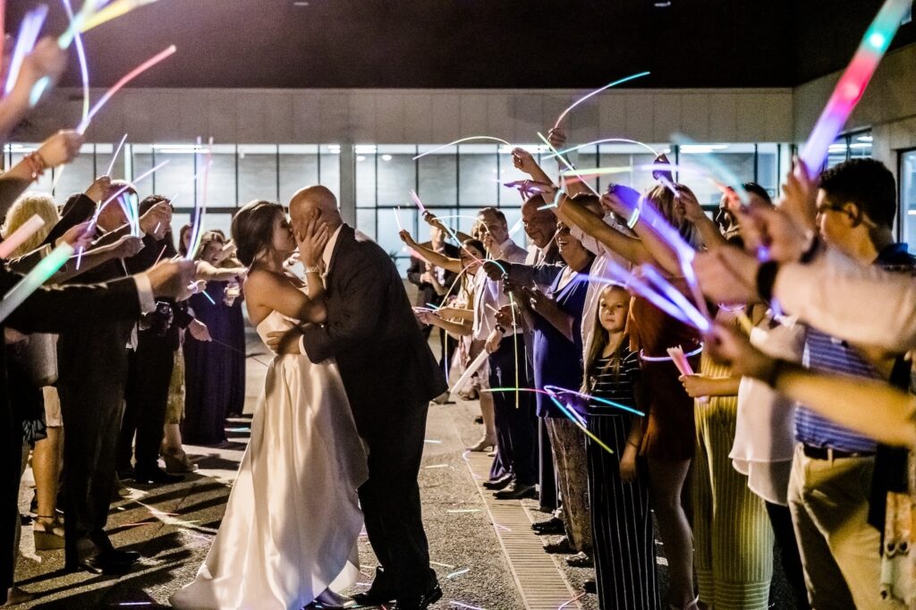 Photo of bride and groom leaving their wedding reception in VBC Saturn Ballroom with guests waving