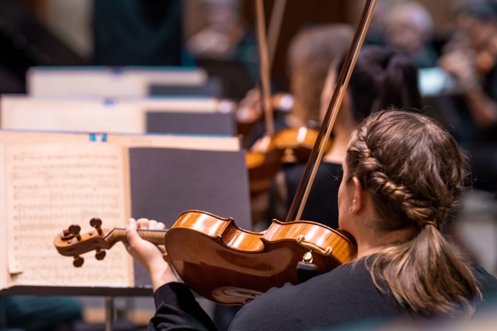 Photo taken from behind violinist reading sheet music during practice