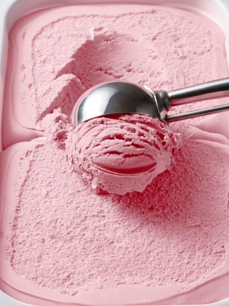 Photo of strawberry ice cream being scooped out of serving container